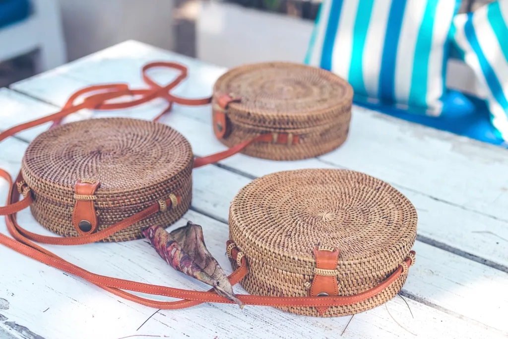 Bolsos tejidos con correa de cuero color miel sobre mesa de madera
