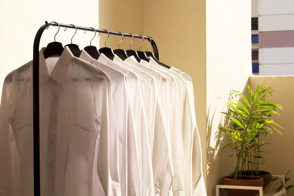 Camisas blancas colgadas en un perchero con luz de la tarde