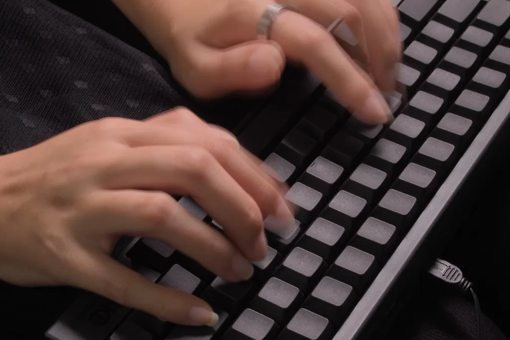 Manos trabajando sobre un teclado en luz tenue